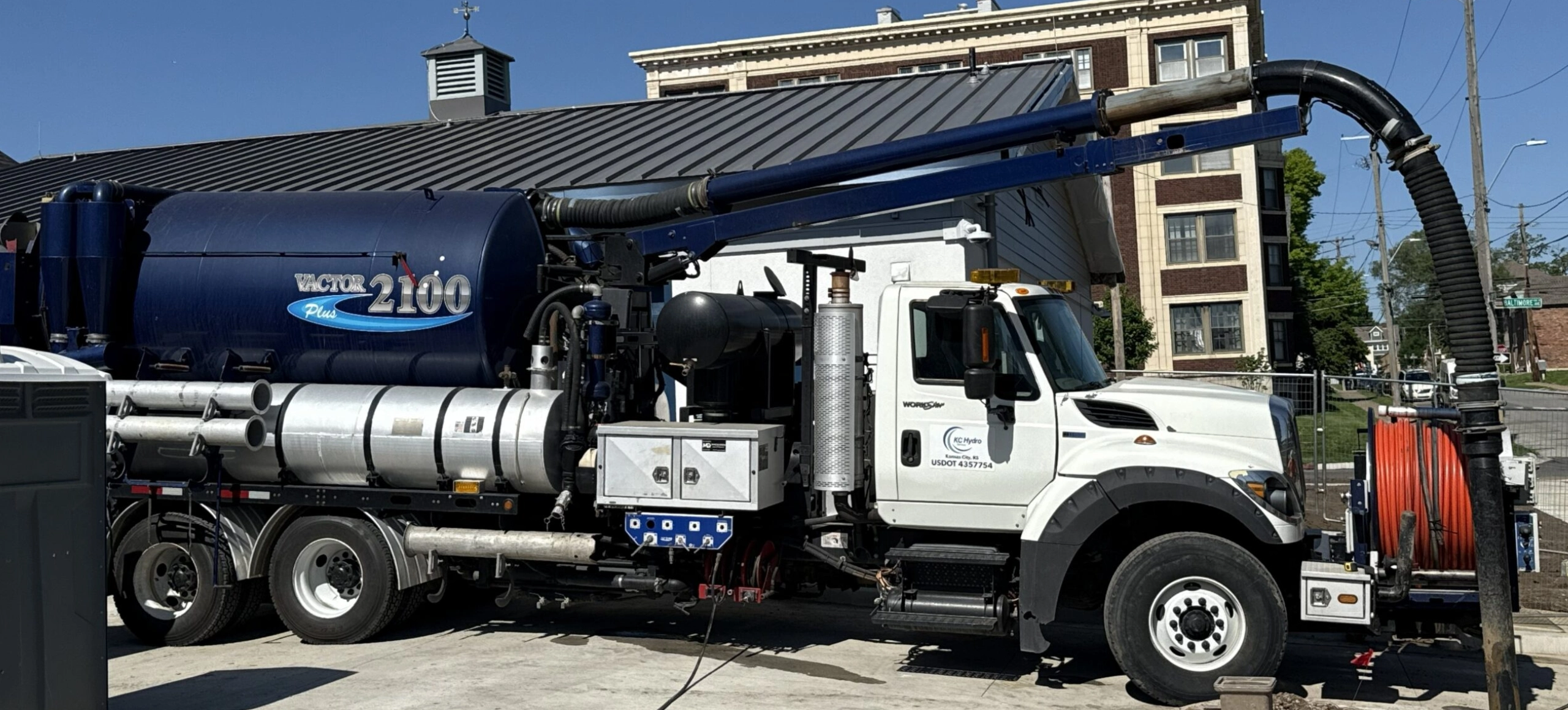 White industrial vacuum truck parked outside a building.